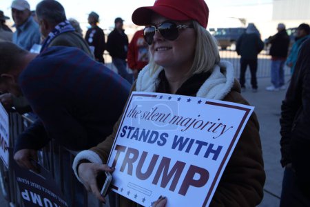 Téléchargez les photos : UNITED-STATES, Mesa : A campaign supporter holds up a sign for Republican presidential candidate Donald Trump as his plane arrives to a campaign event at the International Air Response facility on December 16, 2015 in Mesa, Arizona. - en image libre de droit