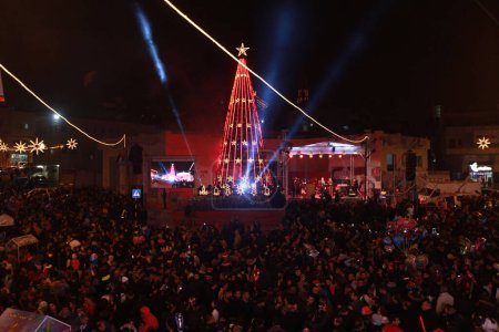 Photo for WEST BANK, Beit Sahour: Thousands of Palestinians attend a Christmas tree lighting festival in the village of Beit Sahour, eastern Bethlehem, West Bank, on December 17, 2015. Musicians played bagpipes, drums and brass before gathering with the crowd - Royalty Free Image