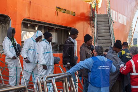 Photo for ITALY, Palermo: Migrants are seen disembarking from the military Norwegian ship Siem Pilot in Palermo on December 28, 2015. Among them 841 men, 64 women, and 26 children came from 30 different nationalities including Morocco - Royalty Free Image