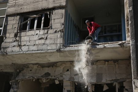 Foto de SIRIA, Saqba: Un residente de la ciudad de Saqba limpia un edificio destruido de la ciudad de East suburbio de Damasco, la capital de Siria, el 28 de diciembre de 2015. - Imagen libre de derechos