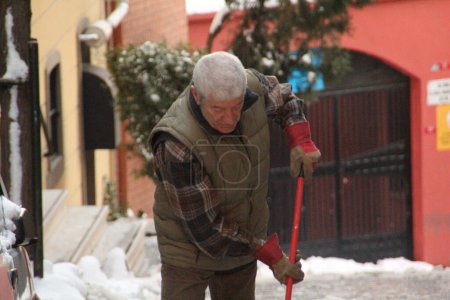 Photo for TURKEY, Istanbul: A man shovels as snow blankets Istanbul, Turkey for a third day on January 1, 2016, grounding 529 flights and nearly 30,000 passengers by January 4. - Royalty Free Image
