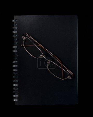 Foto de Cuaderno y gafas sobre fondo oscuro - Imagen libre de derechos