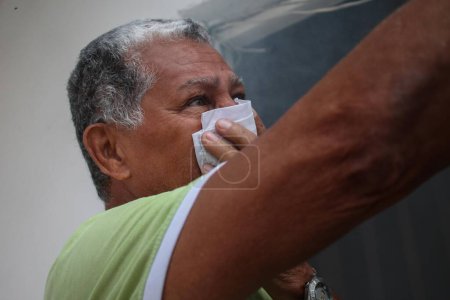 Photo for VENEZUELA, Caracas: A resident of Caracus, Venezuela protects himself from smoke as fumigation crews work to exterminate mosquitoes carrying the Zika virus in the slums of Caracas, Venezuela on February 3, 2016. - Royalty Free Image