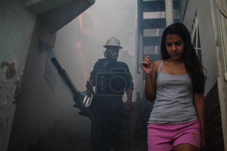Photo for VENEZUELA, Caracas: A member of a fumigation crew waits for a girl to exit her home to allow for the extermination of Aedes mosquitoes carrying the Zika virus in the slums of Caracas, Venezuela on February 3, 2016. - Royalty Free Image