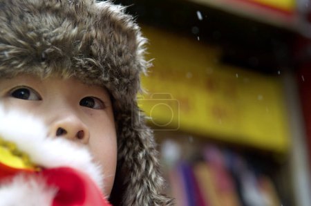 Téléchargez les photos : États-Unis, New York : Un petit garçon assiste aux festivités de la danse Chinatown de New York avec des dragons et marche à travers une neige légère le 8 février 2016 pour célébrer le Nouvel An lunaire. - en image libre de droit