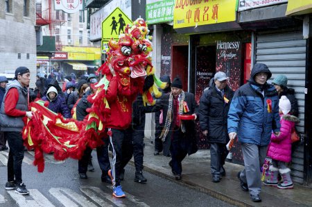 Téléchargez les photos : États-Unis, New York : Des fêtards dans la danse Chinatown de New York avec des dragons alors qu'ils marchent dans une neige légère le 8 février 2016 pour célébrer le Nouvel An lunaire. - en image libre de droit
