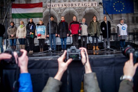 Téléchargez les photos : HONGRIE, Budapest : Les participants à une manifestation pour les enseignants, les parents et leurs sympathisants tiennent des banderoles et des parapluies devant le bâtiment du Parlement à Budapest le 13 février 2016 - en image libre de droit