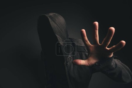 Photo for Spooky hooded person without face in dark room - Royalty Free Image