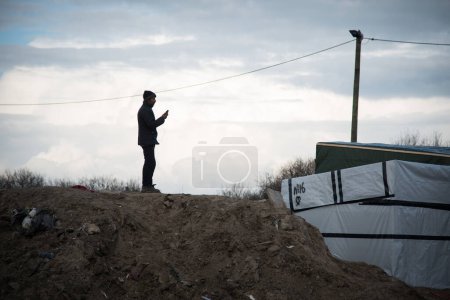 Photo for FRANCE, Calais: Employees of the prefecture of Calais and volunteers are seen in the Jungle migrant camp of Calais, northern France, on February 26, 2016, as they inform migrants on the eviction order - Royalty Free Image