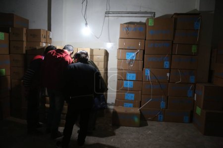 Foto de SIRIA, Kafr Batna: El personal de la Media Luna Roja Siria inspecciona la entrega de ayuda humanitaria en un almacén en Kafr Batna, en la zona de Guta Oriental, al sur de Siria, en las afueras de la capital Damasco, el 23 de febrero de 2016 - Imagen libre de derechos