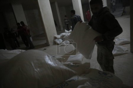 Foto de SIRIA, Kafr Batna: El personal de la Media Luna Roja Siria inspecciona la entrega de ayuda humanitaria en un almacén en Kafr Batna, en la zona de Guta Oriental, al sur de Siria, en las afueras de la capital Damasco, el 23 de febrero de 2016 - Imagen libre de derechos