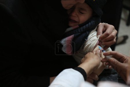 Foto de SYRIA, Ghouta: Un niño sirio recibe una vacuna durante una campaña organizada por la Media Luna Roja Árabe Siria SARC en la zona de Guta Oriental, en las afueras de la capital, Damasco, el 3 de marzo de 2016. - Imagen libre de derechos