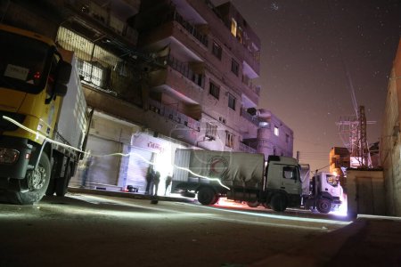 Foto de SIRIA, Saqba: Un camión, parte de un tan esperado convoy de las Naciones Unidas, se encuentra junto a un edificio volado en Saqba, justo al este de Damasco, Siria, el 4 de marzo de 2016. - Imagen libre de derechos