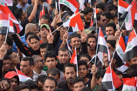 Foto de IRAQ, Bagdad: Decenas de miles de personas marcharon en Bagdad el 4 de marzo de 2016 en apoyo del clérigo chiíta iraquí Muqtada al-Sadr, agitando banderas nacionales y gritando consignas durante una manifestación por reformas gubernamentales y contra la corrupción - Imagen libre de derechos
