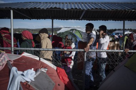 Foto de GRECIA, Idomeni: Los refugiados se reúnen en las vías del ferrocarril en la frontera greco-macedonia cerca de la aldea griega de Idomeni, donde miles de refugiados y migrantes están atrapados por el bloqueo fronterizo de los Balcanes, el 9 de marzo de 2016 - Imagen libre de derechos
