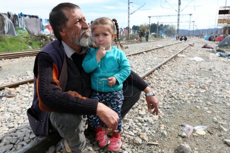 Photo for GREECE, Idomeni: Refugees gather on the railroad tracks at the Greek-Macedonian border near the Greek village of Idomeni, where thousands of refugees and migrants are trapped by the Balkan border blockade, on March 9, 2016 - Royalty Free Image