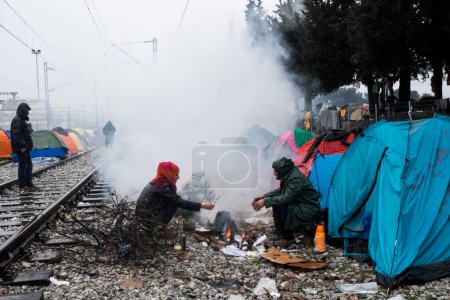 Foto de Grecia, Idomeni - 05 de marzo de 2016: La gente hace cola para comer en un campo de refugiados en la frontera entre Grecia y Macedonia - Imagen libre de derechos