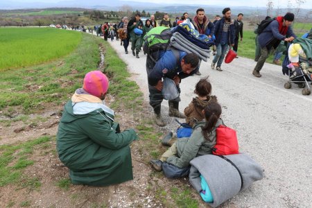 Téléchargez les photos : Grèce, Idomeni - 14 mars 2016 : Des migrants et des réfugiés traversent une rivière qui monte en flèche en route vers la Macédoine depuis un camp de fortune à la frontière gréco-macédonienne, près du village grec d'Idomeni - en image libre de droit
