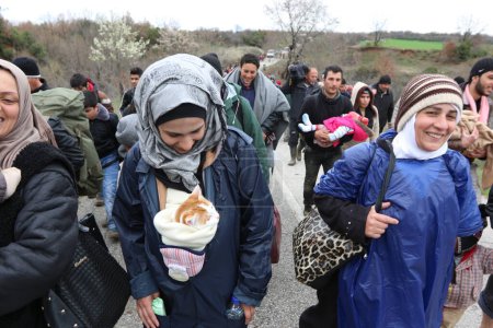 Foto de Grecia, Idomeni - 14 de marzo de 2016: Migrantes y refugiados cruzan un río en ascenso camino a Macedonia desde un campamento improvisado en la frontera greco-macedonia, cerca de la aldea griega de Idomeni - Imagen libre de derechos