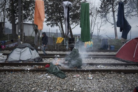 Téléchargez les photos : GRÈCE, Idomeni : Des réfugiés se rassemblent sur les voies ferrées à la frontière gréco-macédonienne près du village grec d'Idomeni, où des milliers de réfugiés et de migrants sont piégés par le blocus frontalier des Balkans, le 9 mars 2016 - en image libre de droit