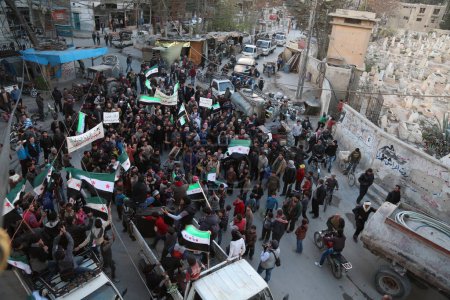 Téléchargez les photos : SYRIE, Saqba : Des centaines de Syriens tiennent un drapeau syrien pré-Baas, adopté par la révolution syrienne lors du soulèvement, le 16 mars 2016 à Saqba - en image libre de droit