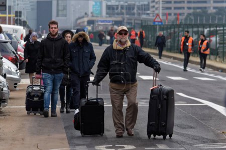 Téléchargez les photos : BELGIQUE, Bruxelles : Des passagers quittent l'aéroport de Bruxelles, le 22 mars 2016 à Zaventem, à la suite de son évacuation après qu'au moins 13 personnes ont été tuées et 35 blessées alors que des explosions jumelles secouaient le terminal principal de l'aéroport de Bruxelles. - en image libre de droit