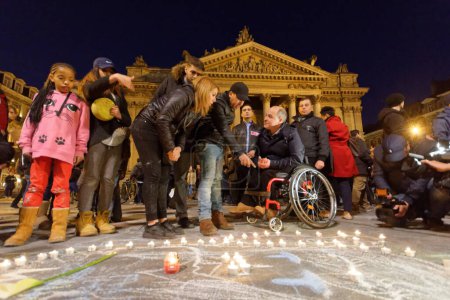 Téléchargez les photos : Belgique, Bruxelles - 22 mars 2016 : Des milliers de personnes se rassemblent autour d'un mémorial improvisé pour rendre hommage aux victimes des attentats à la bombe, sur la Place de la Bourse, à Bruxelles, en Belgique - en image libre de droit