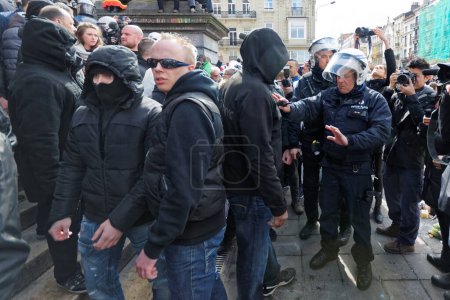 Photo for BELGIUM, Brussels: Far-right football hooligans chant slogans as they stand in the square outside the stock exchange in Brussels on March 27, 2016 - Royalty Free Image