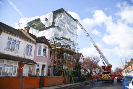 Photo for UNITED KINGDOM, London: Firefighters attempt to secure a scaffolding which partly collapsed on a house ater storm Katie hits the area, in Lealand Road, in Tottenham neighborhood, northern London, on March 28, 2016. - Royalty Free Image