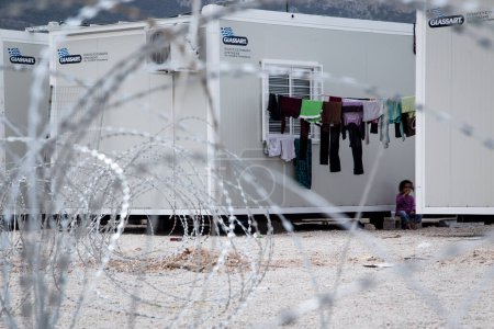 Foto de GRECIA, Skaramagas: Mientras miles de refugiados permanecen varados en Grecia, una familia se sienta en uno de los varios contenedores de almacenamiento que sirven a hogares para 1.000 personas en un nuevo campamento en Skaramagas, cerca de Atenas, el 14 de abril de 2016.. - Imagen libre de derechos