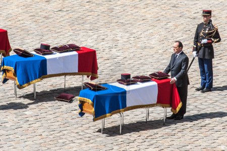 Foto de FRANCIA, París: El presidente francés Francois Hollande rinde homenaje frente a uno de los tres ataúdes con los cuerpos de tres soldados franceses muertos en servicio en Malí la semana pasada, durante una ceremonia solemne y nacional de homenaje - Imagen libre de derechos