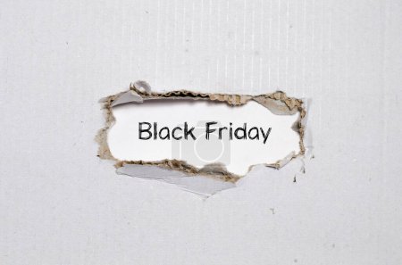 Téléchargez les photos : Les mots vendredi noir apparaissant derrière le papier déchiré - en image libre de droit