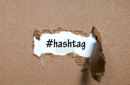 Téléchargez les photos : Le mot hashtag apparaissant derrière le papier déchiré - en image libre de droit
