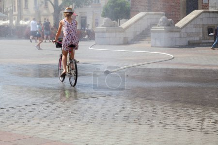 Téléchargez les photos : Les gens qui utilisent un rideau d'eau dans une journée chaude ensoleillée, Cracovie, Pologne - en image libre de droit