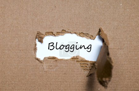 Téléchargez les photos : Le mot blogging apparaissant derrière le papier déchiré - en image libre de droit