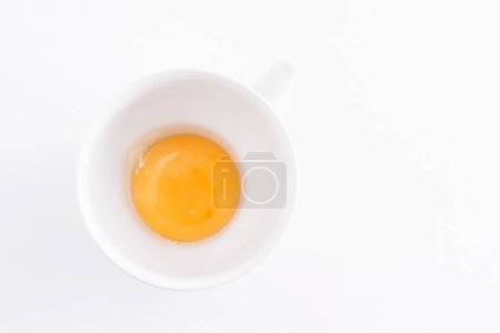 Photo for Raw egg yolk in a bowl on a white background - Royalty Free Image