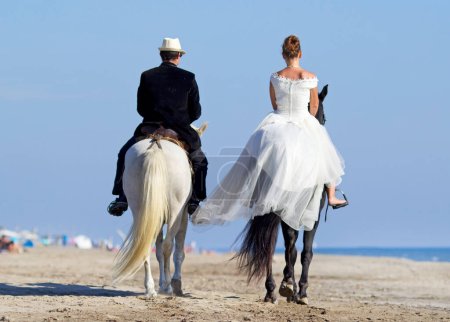Téléchargez les photos : Jeune couple de mariage sur la plage à cheval - en image libre de droit