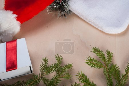 Téléchargez les photos : Un cadeau de Noël avec un chapeau de Père Noël et des branches de sapin - en image libre de droit