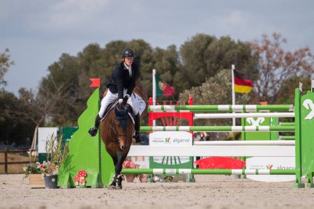Téléchargez les photos : VILAMOURA, PORTUGAL - APRIL 3, 2016: Horse obstacle jumping competition - en image libre de droit