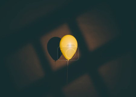 Foto de Un disparo vertical de un globo amarillo con un fondo negro - Imagen libre de derechos