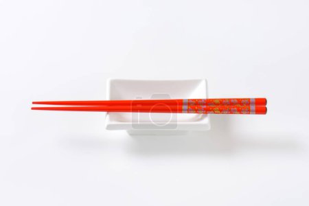 Photo for Red chopsticks on soy sauce dish - Royalty Free Image