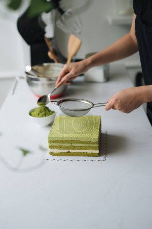 Foto de Verter té verde en polvo sobre delicioso pastel de queso - Imagen libre de derechos