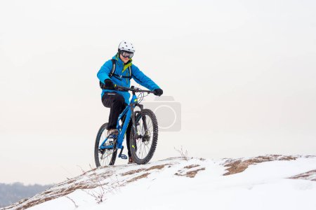Téléchargez les photos : Cycliste au repos bleu avec VTT sur une colline d'hiver rocheuse. Concept de vélo sport extrême et enduro. - en image libre de droit
