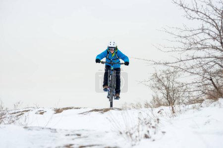 Photo for Cyclist in blue resting with mountain bike on rocky winter hill. Extreme sport and enduro biking concept. - Royalty Free Image