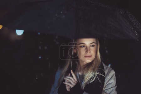 Photo for Thoughtful woman outdoors on rainy night - Royalty Free Image