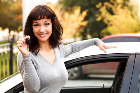 Téléchargez les photos : Heureux propriétaire d'une nouvelle voiture, souriant jeune fille mignonne montrant une clé - en image libre de droit