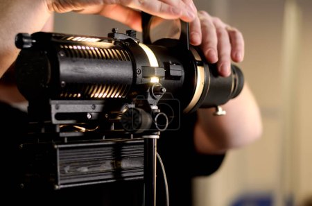 Téléchargez les photos : "Homme ajuste projecteur film professionnel ampoule" - en image libre de droit