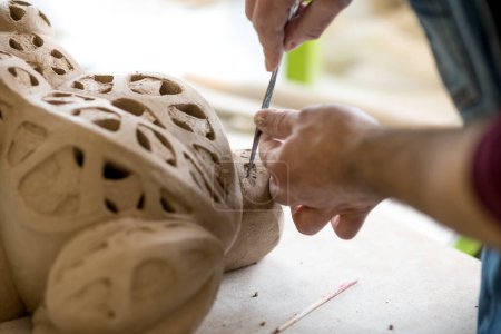 Foto de Ceramista vestido con un delantal esculpir estatua de arcilla cruda en brillante taller de cerámica - Imagen libre de derechos