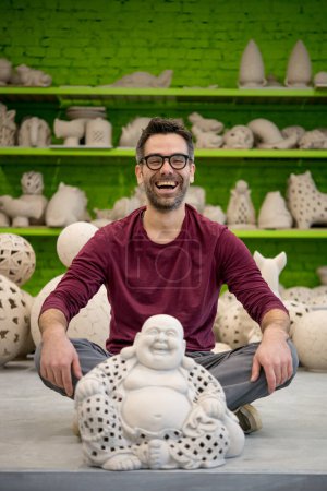 Photo for Portrait of Smiling Young Ceramist in the Bright Modern Ceramic Workshop Sitting Next to Sculpture. Small Business Concept - Royalty Free Image
