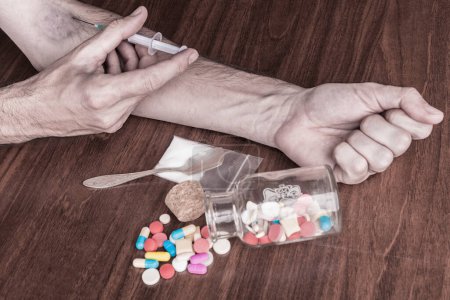 Téléchargez les photos : Toxicomane dans une héroïne, une seringue et une héroïne sur une table en bois - en image libre de droit